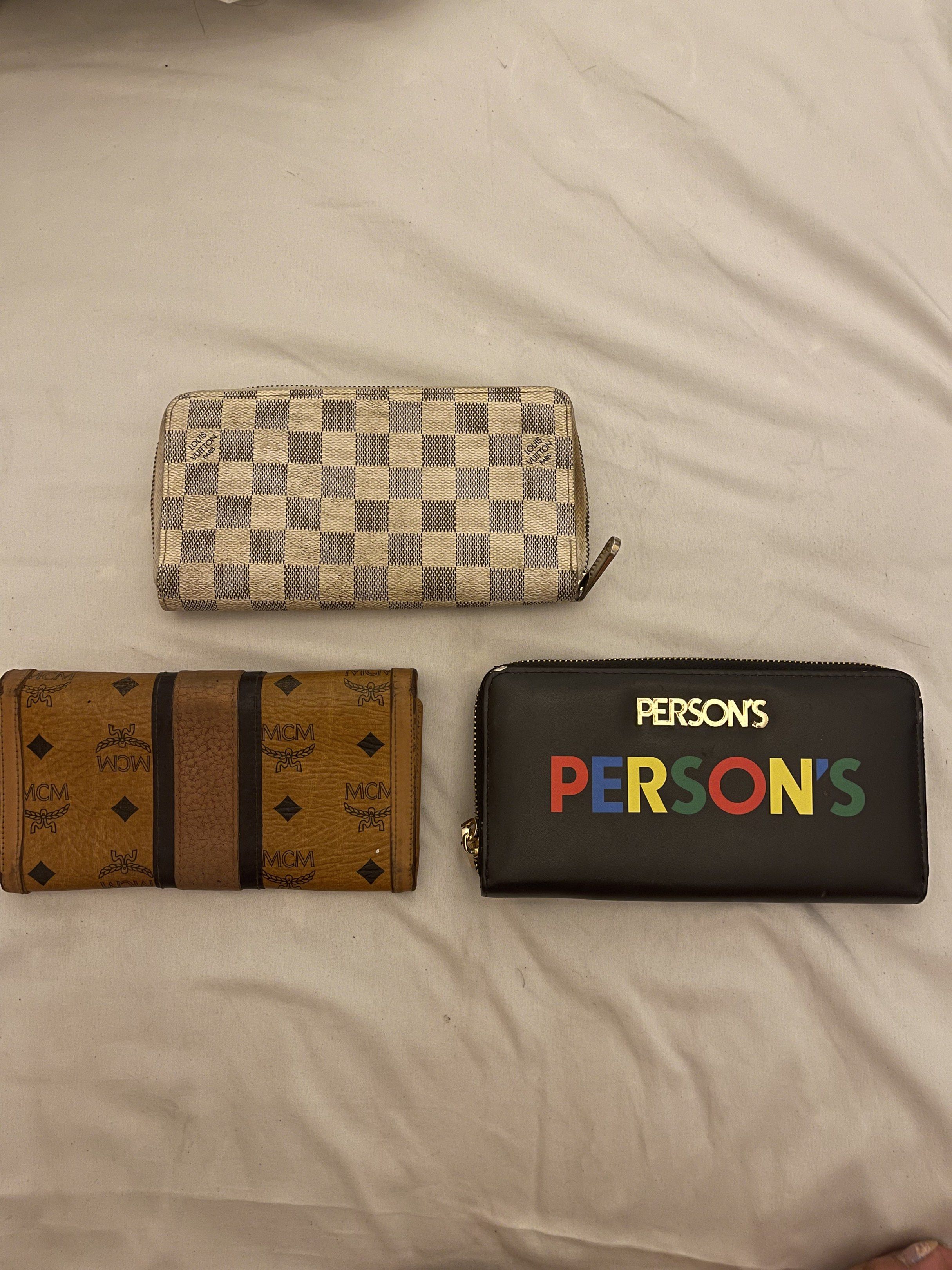 Louis Vuitton, MCM, and Person's Wallets (Category: Luxury Bags & Wallets) located in Marilao. Submitted by wardrovearchives (Listing ID 1419302296, Image 1). Description: - Checkered pattern wallet with zipper (used). - Brown wallet with MCM logo (used). - Black wallet with "PERSON'S" in colorful letters (used). 📌 Sold as bundle only 📌 What you see is what you get 📌 Photos shown are the only photos available 📌 No individual or detailed photo