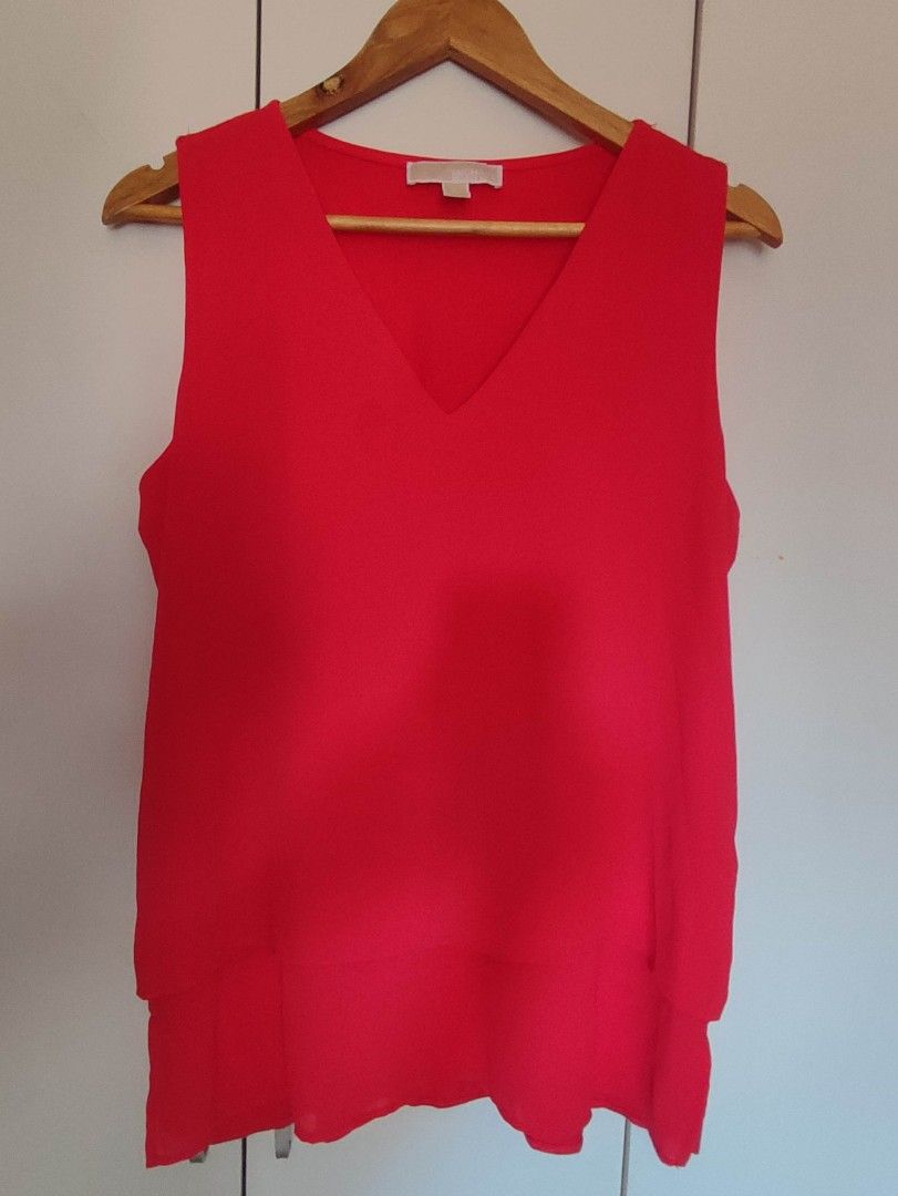 Michael Kors Sleeveless V-Neck Top (Category: Sleeveless) located in Mangaldan. Submitted by michelle_2004 (Listing ID 1419289155, Image 1). Description: Bright red sleeveless top from Michael Kors. Features a V-neck design. The tag indicates the size is L. The top has a layered design at the bottom. The Michael Kors logo is visible on the neckline..