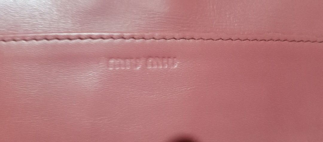 Miu Miu Leather Wallet (Category: Luxury Bags & Wallets) located in Makati City. Submitted by cd910625 (Listing ID 1419236132, Image 2). Description: Miu Miu wallet features a bi-fold design with a vibrant orange exterior and a pink interior. It has multiple card slots, a zippered compartment, and a snap closure. The Miu Miu logo is visible on the exterior and the zipper pull..