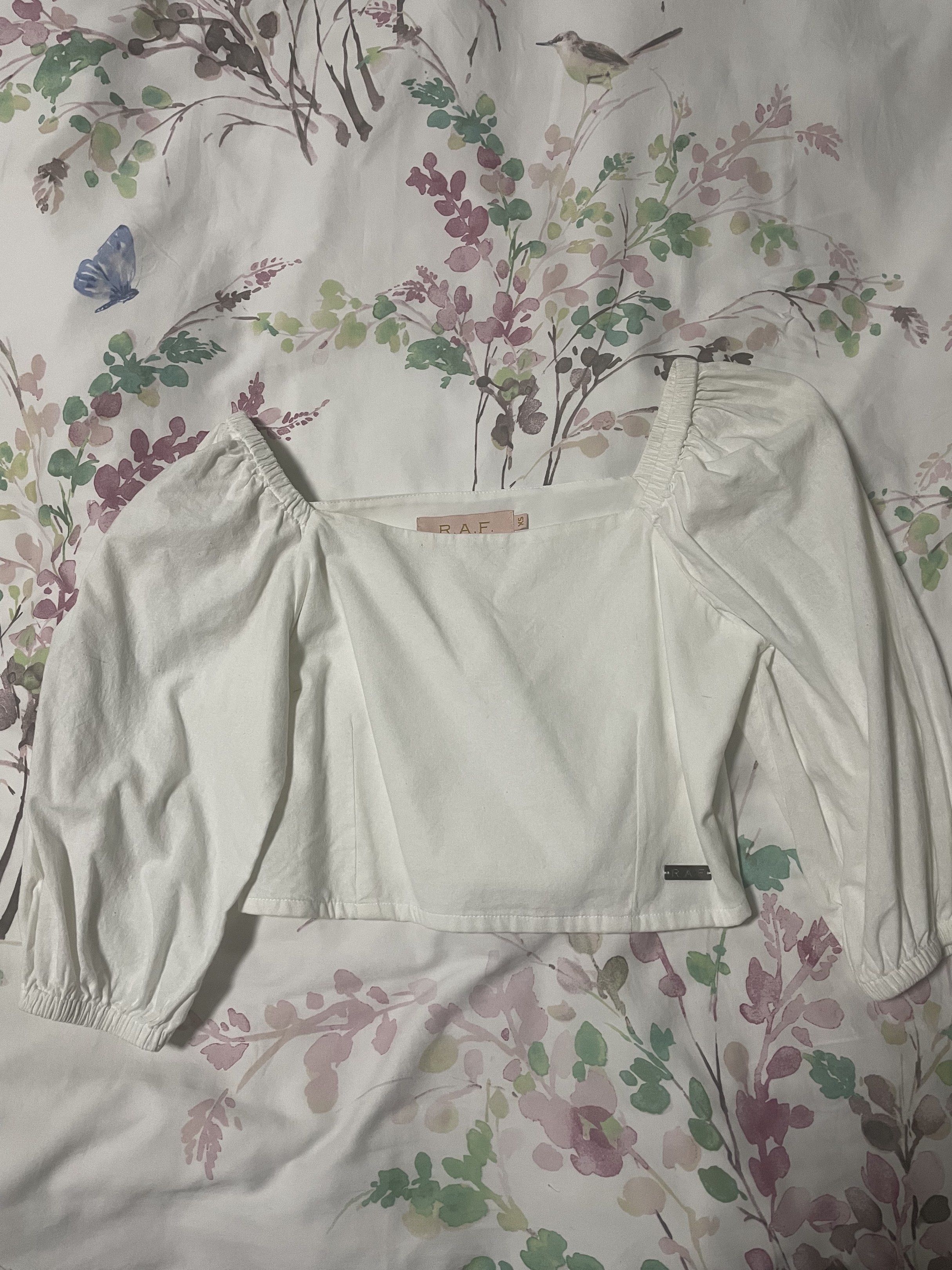 R.A.F. White Top XS (Category: Sleeveless) located in Quezon City. Submitted by lillyshop (Listing ID 1419337976, Image 1). Description: - R.A.F. white cropped top - Size: XS - Features a square neckline - Long, puffed sleeves - Lightweight fabric - Small logo detail.