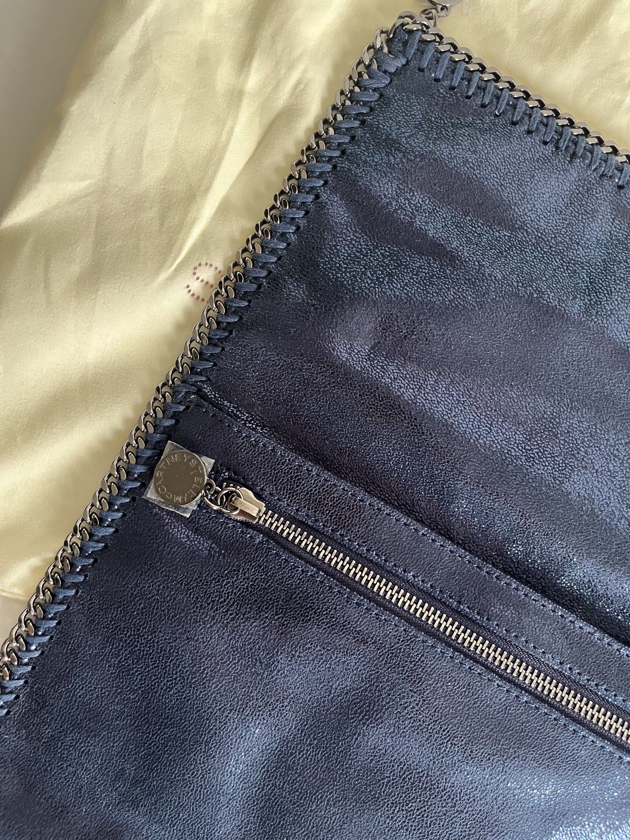 Stella McCartney Falabella Clutch (Category: Luxury Bags & Wallets) located in Manila. Submitted by mentone (Listing ID 1419258219, Image 2). Description: - Navy blue Stella McCartney Falabella clutch - Chain trim detail - Magnetic snap closure - Interior zippered pocket - Light pink interior lining - Includes dust bag - Metallic sheen.