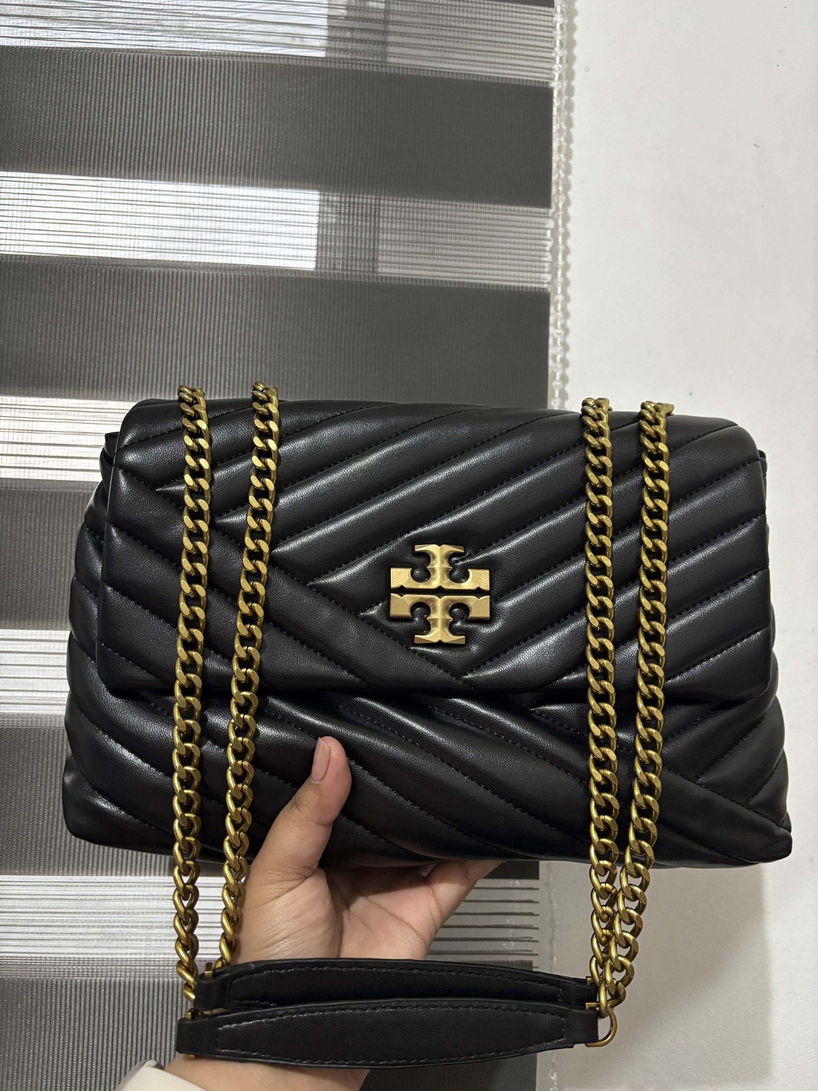 Tory Burch Kira Chevron Shoulder Bag (Category: Luxury Bags & Wallets) located in Magalang. Submitted by katoenjeru0723 (Listing ID 1419295193, Image 1). Description: - Authentic Tory Burch Kira Chevron shoulder bag - Classic black color with gold-tone hardware - Stylish quilted chevron design - Features a convenient chain strap - Secure flap closure with magnetic snap - Includes original tag - Interior with zip pocket - Perfect for everyday use.