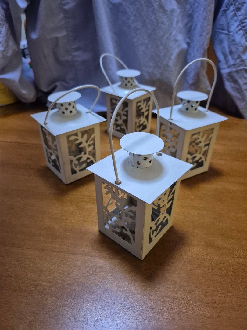 White Decorative Lanterns for Tealights (Category: Lighting) located in Quezon City. Submitted by imraedi (Listing ID 1419284945, Image 2). Description: 4 lamps take all - Set of white decorative lanterns - Square shape with intricate cut-out designs - Made of metal - Features a handle - Designed for candles or small light sources - Adds an elegant touch to any space - Glass protected (1 lantern has 1 side with glass left).