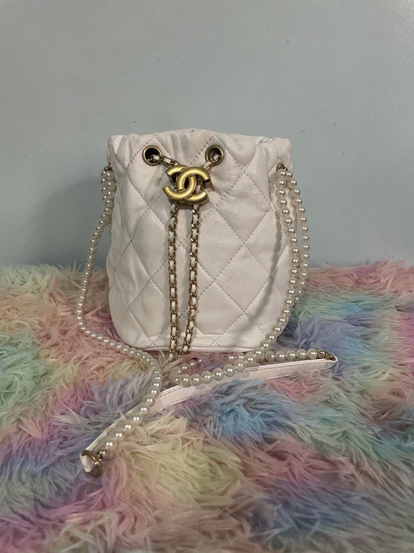Chanel Quilted Bucket Bag with Pearl Strap (Category: Luxury Bags & Wallets) located in Pasig City. Submitted by ladyboss1012 (Listing ID 1422483728, Image 1). Description: - White quilted bucket bag - Pearl strap and gold-tone chain drawstring - Gold-tone Chanel logo - Red interior with Chanel label - Chanel logo stitched on the bottom - Made in Italy.