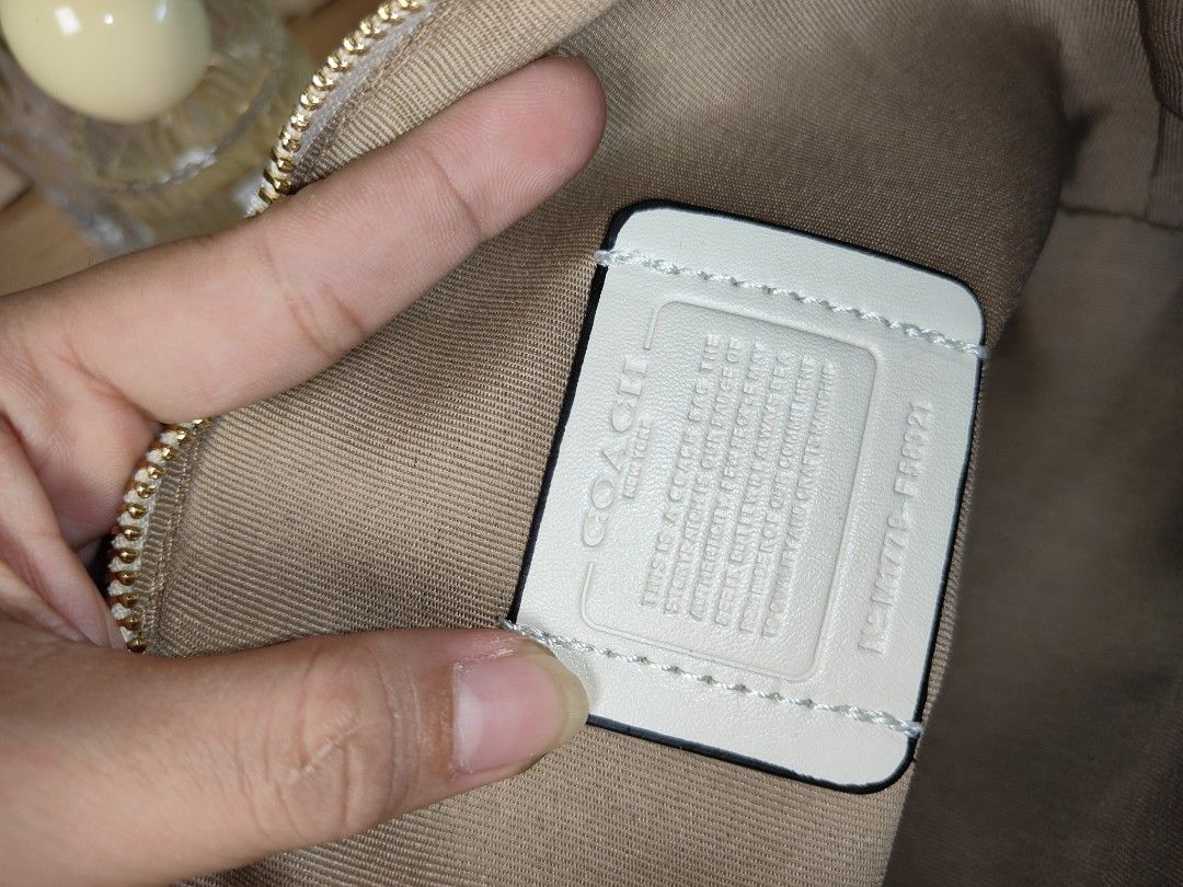 Coach Signature Mini Tote Bag (Category: Luxury Bags & Wallets) located in Naga. Submitted by demaria14 (Listing ID 1422511577, Image 3). Description: - Coach Mini Tote Bag - Signature pattern - Top zip closure - Dual top handles - Adjustable, detachable crossbody strap - Coach hangtag included - Interior slip pocket - Coach leather patch - Gold-tone hardware - Beige and white color.
