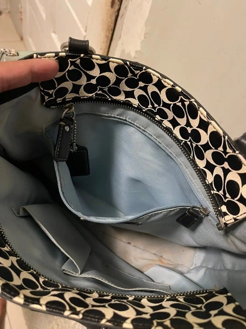 Coach Signature Tote Bag (Category: Luxury Bags & Wallets) located in Andop. Submitted by source8600 (Listing ID 1422541107, Image 3). Description: - Coach tote bag - Black and white signature pattern - Black leather handles and trim - Light blue interior lining - - Multiple compartments and zippered pocket - Includes Coach leather tag - Top zipper closure.