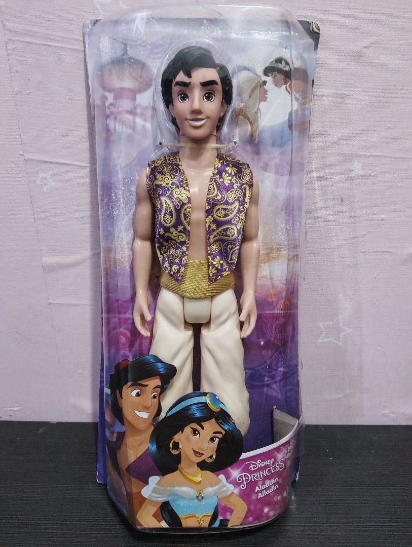 Disney Aladdin Prince Aladdin Doll (Category: Figurines & Statues) located in Angono. Submitted by lala_tan (Listing ID 1422538296, Image 1). Description: Disney Prince Aladdin doll. The doll is in its original packaging. Aladdin is wearing a purple vest with gold accents and white pants. The packaging features images of Aladdin and Princess Jasmine. It is a collectible item for Disney fans..