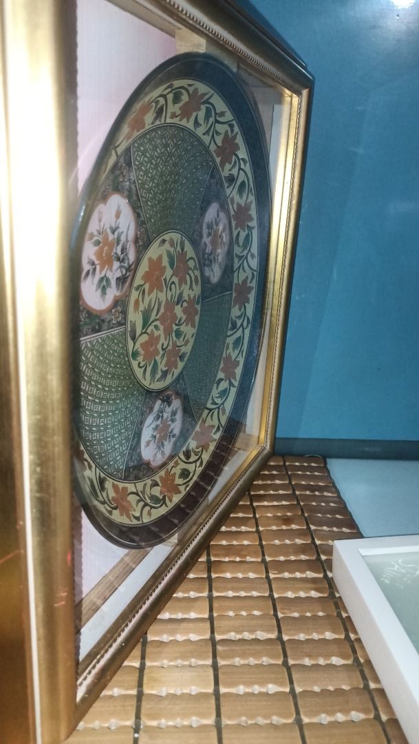 Framed Decorative Oriental Plate (Category: Wall Decor) located in Munoz. Submitted by larryc1212 (Listing ID 1422522025, Image 2). Description: Beautifully framed decorative plate with intricate floral design. The plate is round and features a gold-colored frame. The plate's design includes orange and white flowers on a green and gold background. The plate measures approximately 9.5 inches in diameter. Item may include some scratches due to age,