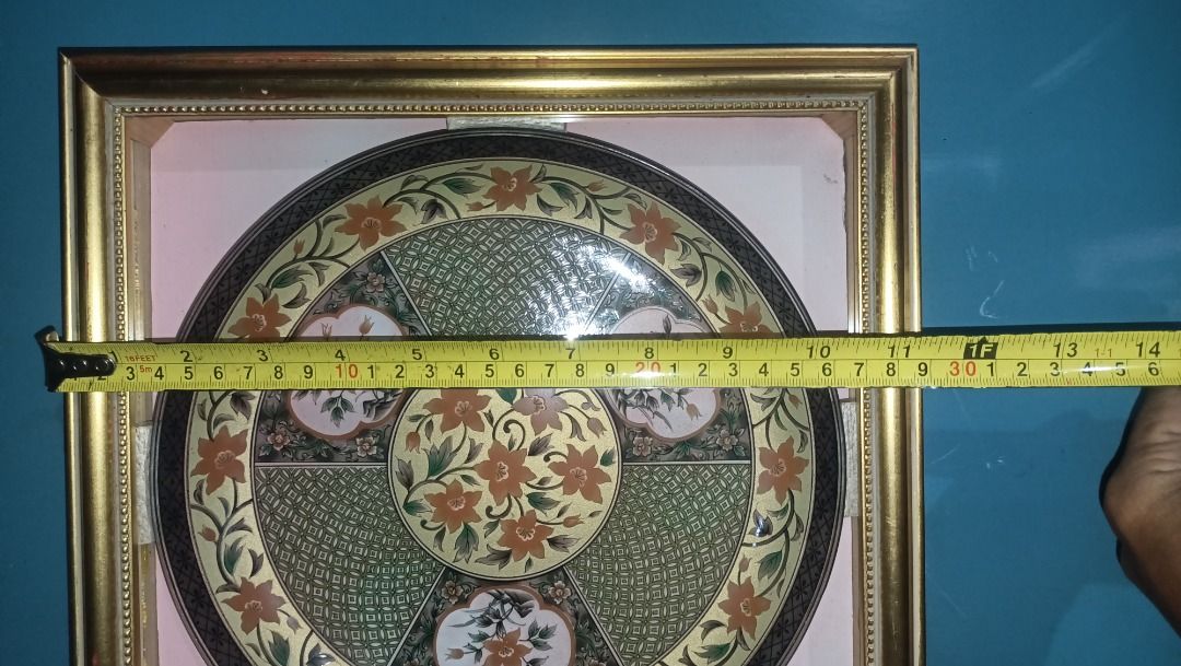 Framed Decorative Oriental Plate (Category: Wall Decor) located in Munoz. Submitted by larryc1212 (Listing ID 1422522025, Image 3). Description: Beautifully framed decorative plate with intricate floral design. The plate is round and features a gold-colored frame. The plate's design includes orange and white flowers on a green and gold background. The plate measures approximately 9.5 inches in diameter. Item may include some scratches due to age,