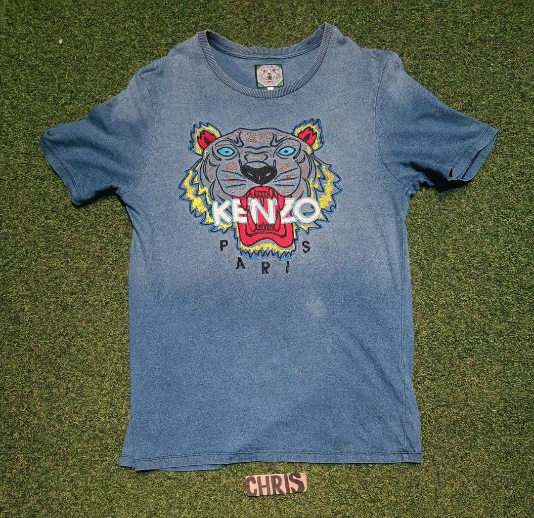 Kenzo Paris Tiger T-shirt (Category: Tshirts & Polo Shirts ) located in Reina Mercedes. Submitted by SIRCHIVES (Listing ID 1422391482, Image 1). Description: - Kenzo Paris T-shirt - Features a bold tiger graphic - Classic crew neck design - Short sleeves for comfort - Prominent Kenzo logo - Constructed from a denim-like fabric.