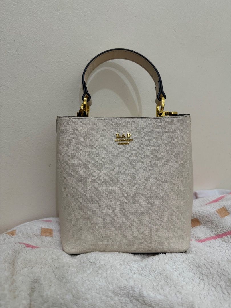 LAP Bucket 2-way Crossbody Bag (Category: Luxury Bags & Wallets) located in Subic. Submitted by e-clutter (Listing ID 1422530587, Image 1). Description: - Cream-colored bucket bag - Top handle and detachable shoulder strap - Gold-colored hardware.