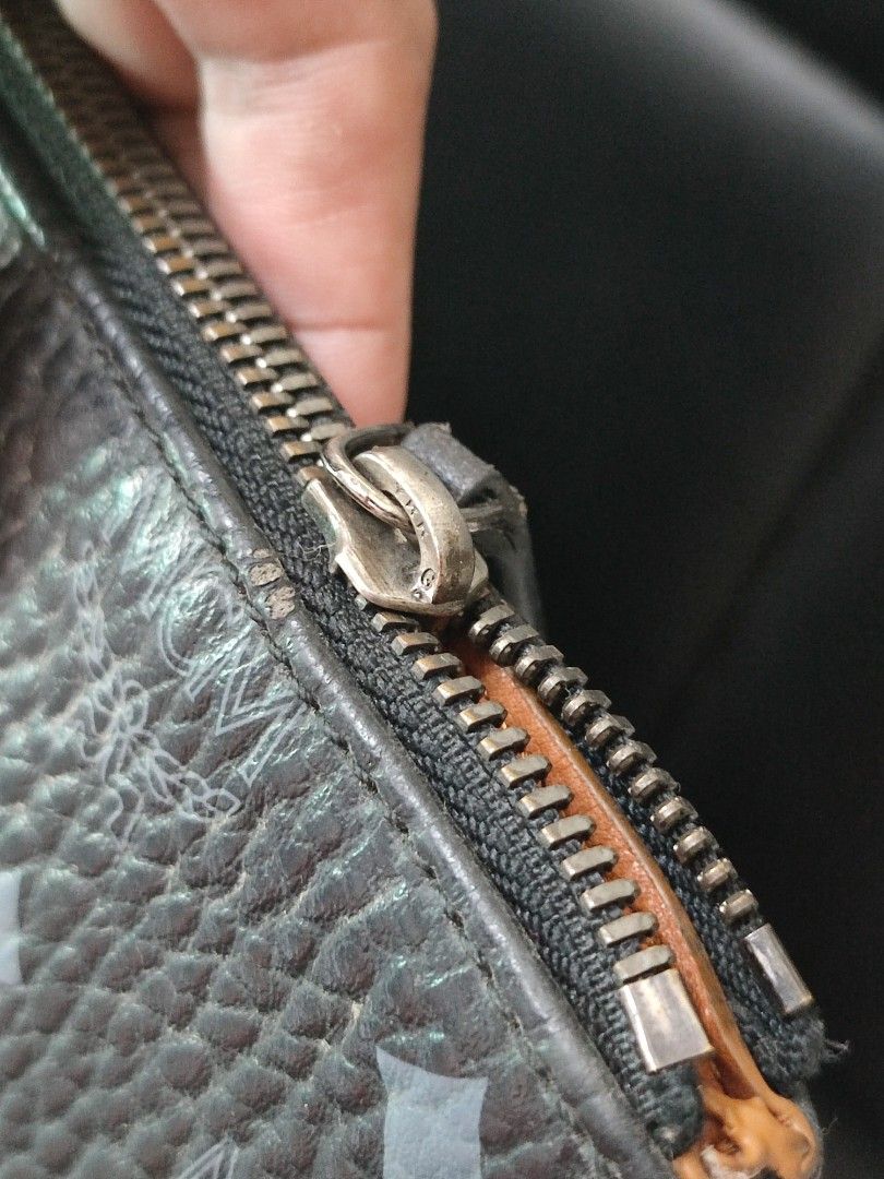 MCM Black Clutch (Category: Luxury Bags & Wallets) located in Basud. Submitted by ClaireLavin (Listing ID 1422395797, Image 3). Description: - MCM clutch - Black with MCM logo pattern - Zip closure - Interior: secondary zip pocket, leather brown lining - Includes wrist strap - Silver-tone zipper pull - Minor wear on corners issue: missing front McM metal hardware .