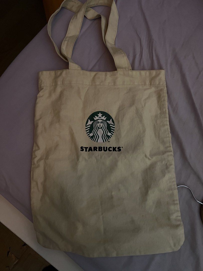 Starbucks Canvas Tote Bag (Category: Tote Bags) located in Cavite. Submitted by cssndrakateg (Listing ID 1422445090, Image 2). Description: - Starbucks canvas tote bag - Beige color - Starbucks logo on the front - Includes an inner pocket - Two handles for carrying.
