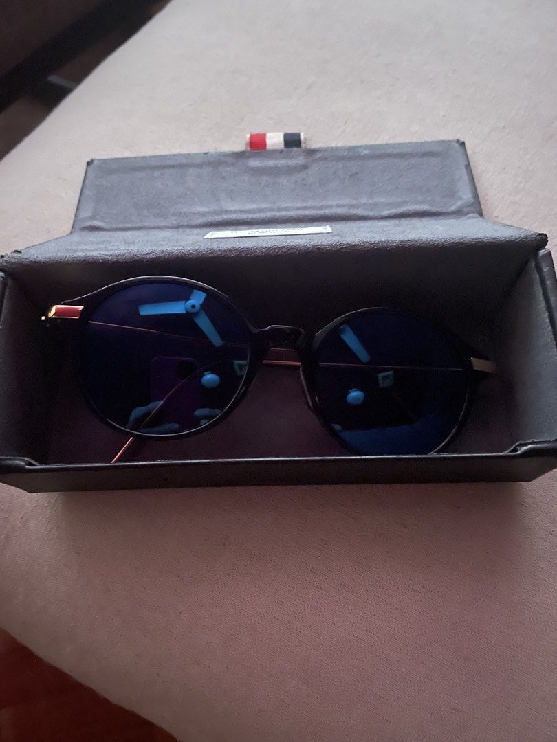 Thom Browne Round Sunglasses (Category: Sunglasses & Eyewear) located in Quezon City. Submitted by deadmit (Listing ID 1422543198, Image 2). Description: - Thom Browne sunglasses - Round frame - Black frame with gold arms - Blue-tinted lenses - Includes Thom Browne case - Case features red, white, and blue stripe - Sleek design for everyday wear Includes original wiper Hardly used.
