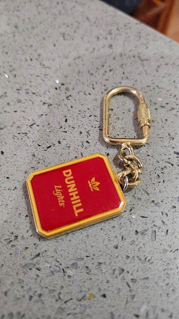Vintage Dunhill Lights Keychain (Category: Luxury Accessories) located in Alfonso. Submitted by jbcamet (Listing ID 1422426222, Image 3). Description: - Vintage Dunhill Lights keychain - Features a red and gold rectangular pendant - Dunhill Lights logo displayed - Includes a gold-colored chain and key ring - Ideal for collectors and vintage item enthusiasts.