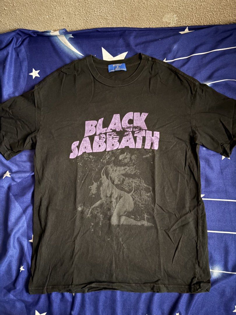 Black Sabbath Graphic Tee (Category: Tshirts & Polo Shirts ) located in Quezon City. Submitted by onlinedeclutterr (Listing ID 1422621115, Image 1). Description: - Black Sabbath graphic tee - Purple print design - Features band name on front - "SA BATH BLOODY SABBATH" on back - Black shirt - Size: Large (based on measurements in photos).