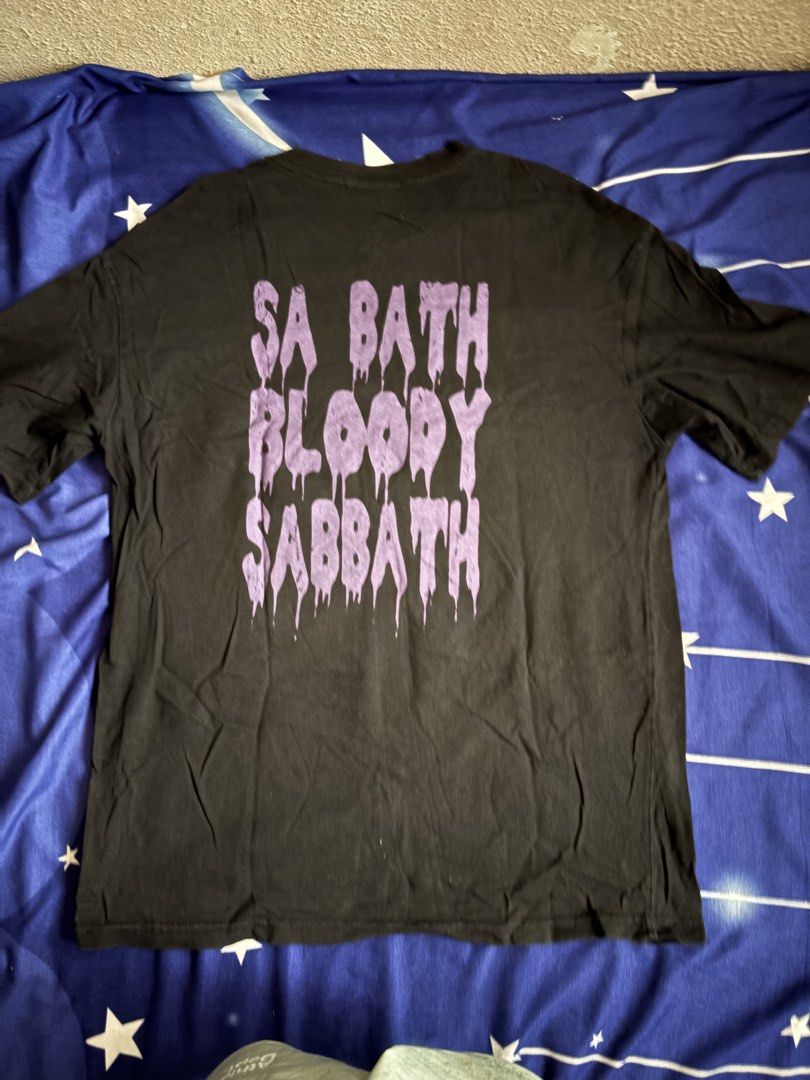 Black Sabbath Graphic Tee (Category: Tshirts & Polo Shirts ) located in Quezon City. Submitted by onlinedeclutterr (Listing ID 1422621115, Image 2). Description: - Black Sabbath graphic tee - Purple print design - Features band name on front - "SA BATH BLOODY SABBATH" on back - Black shirt - Size: Large (based on measurements in photos).