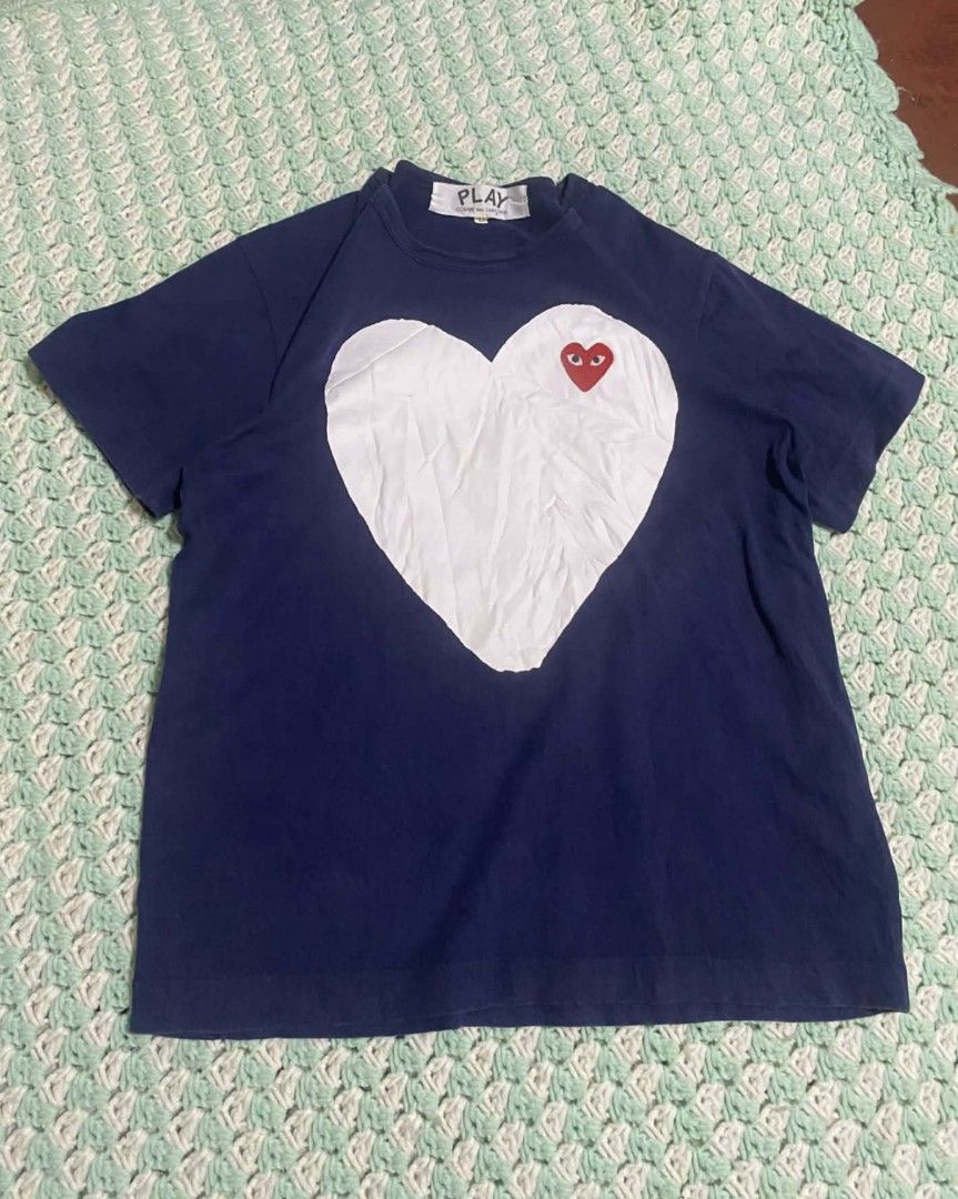 Comme des Garcons Play Heart Logo T-shirt (Category: Shirts) located in Manila. Submitted by jthrift_apparel (Listing ID 1422691496, Image 1). Description: - Comme des Garcons Play T-shirt - Color: Navy blue - Features a white heart graphic with red heart logo - Crew neck - Short sleeves - Made of cotton - "PLAY" label visible on collar.