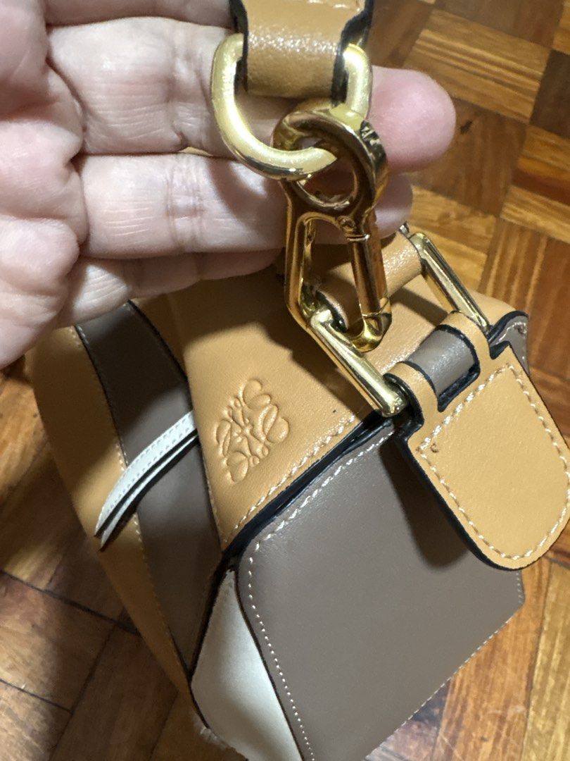 Loewe Puzzle Mini Bag (Category: Luxury Bags & Wallets) located in Mandaluyong City. Submitted by carlaannemarie (Listing ID 1422585963, Image 2). Description: - Loewe Puzzle Mini Bag - Color: Tan, Brown, White - Unique geometric design - Top handle and detachable shoulder strap - Gold-tone hardware - Made of leather - Loewe logo visible.