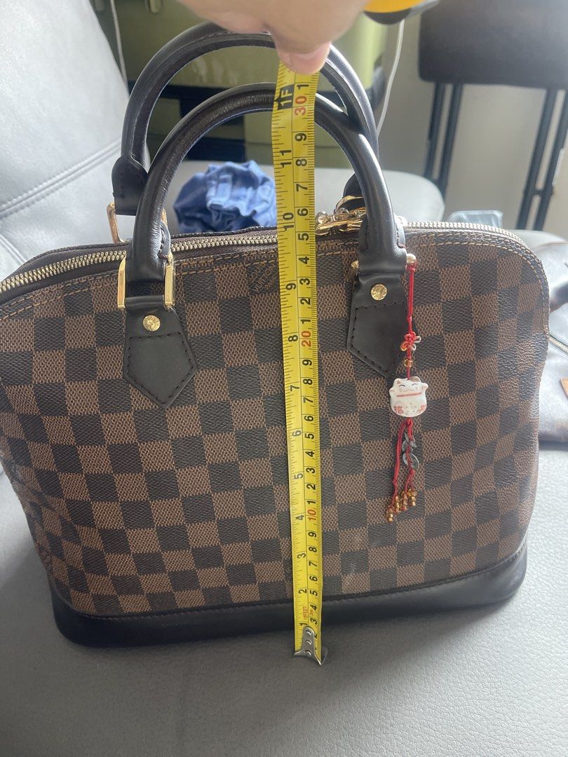 Louis Vuitton Alma Damier Ebene Handbag (Category: Luxury Bags & Wallets) located in San Juan City. Submitted by nhelsky_c (Listing ID 1422567694, Image 1). Description: - japan sourceLouis Vuitton Alma handbag - Damier Ebene canvas - Zip closure - Rolled leather handles - Spacious interior with slip pocket - Brown leather base and trim - Includes decorative charm - Dimensions: Approx. 9" height x 12" width.