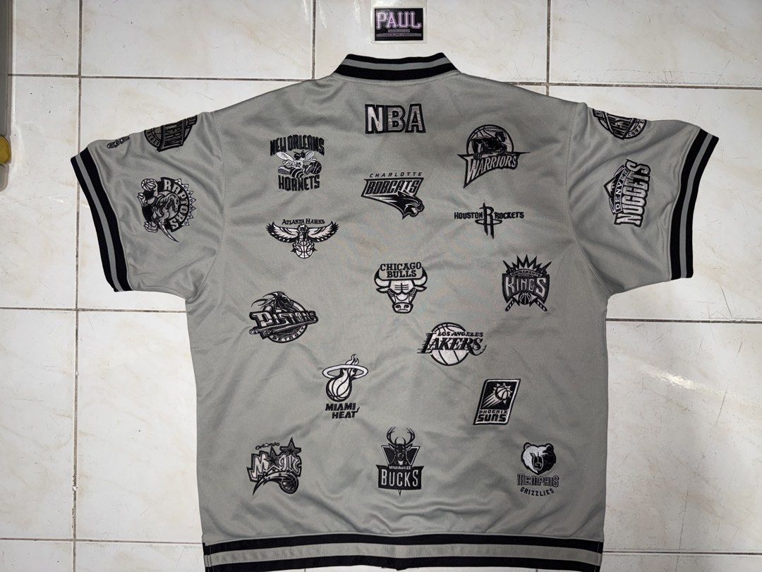 NBA Team Logo Jacket (Category: Coats, Jackets and Outerwear) located in Quezon City. Submitted by bigbad_p (Listing ID 1422690655, Image 2). Description: - Vintage NBA jacket - Features multiple NBA team logos - Gray with black logos and trim - Button-up front - Short sleeves - Black and white striped trim - Retro style.