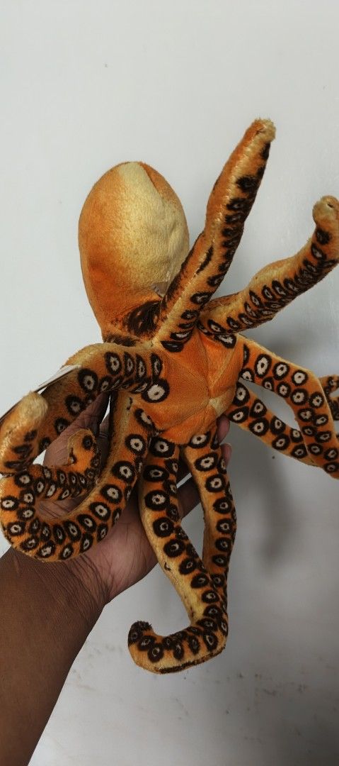 Orange Octopus Plush Toy (Category: Plushies & Soft Toys) located in Polomolok. Submitted by dkljapansurplus (Listing ID 1422585420, Image 3). Description: - Cute orange octopus plushie! - Features brown spots and green eyes. - Soft and huggable design. - Multiple tentacles. - Great for kids and collectors. - See hand for size reference..