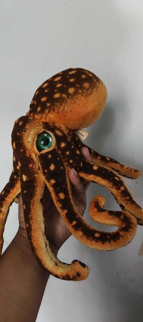 Orange Octopus Plush Toy (Category: Plushies & Soft Toys) located in Polomolok. Submitted by dkljapansurplus (Listing ID 1422585420, Image 2). Description: - Cute orange octopus plushie! - Features brown spots and green eyes. - Soft and huggable design. - Multiple tentacles. - Great for kids and collectors. - See hand for size reference..