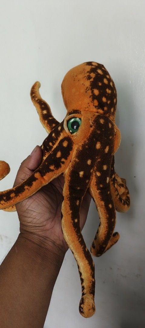 Orange Octopus Plush Toy (Category: Plushies & Soft Toys) located in Polomolok. Submitted by dkljapansurplus (Listing ID 1422585420, Image 1). Description: - Cute orange octopus plushie! - Features brown spots and green eyes. - Soft and huggable design. - Multiple tentacles. - Great for kids and collectors. - See hand for size reference..