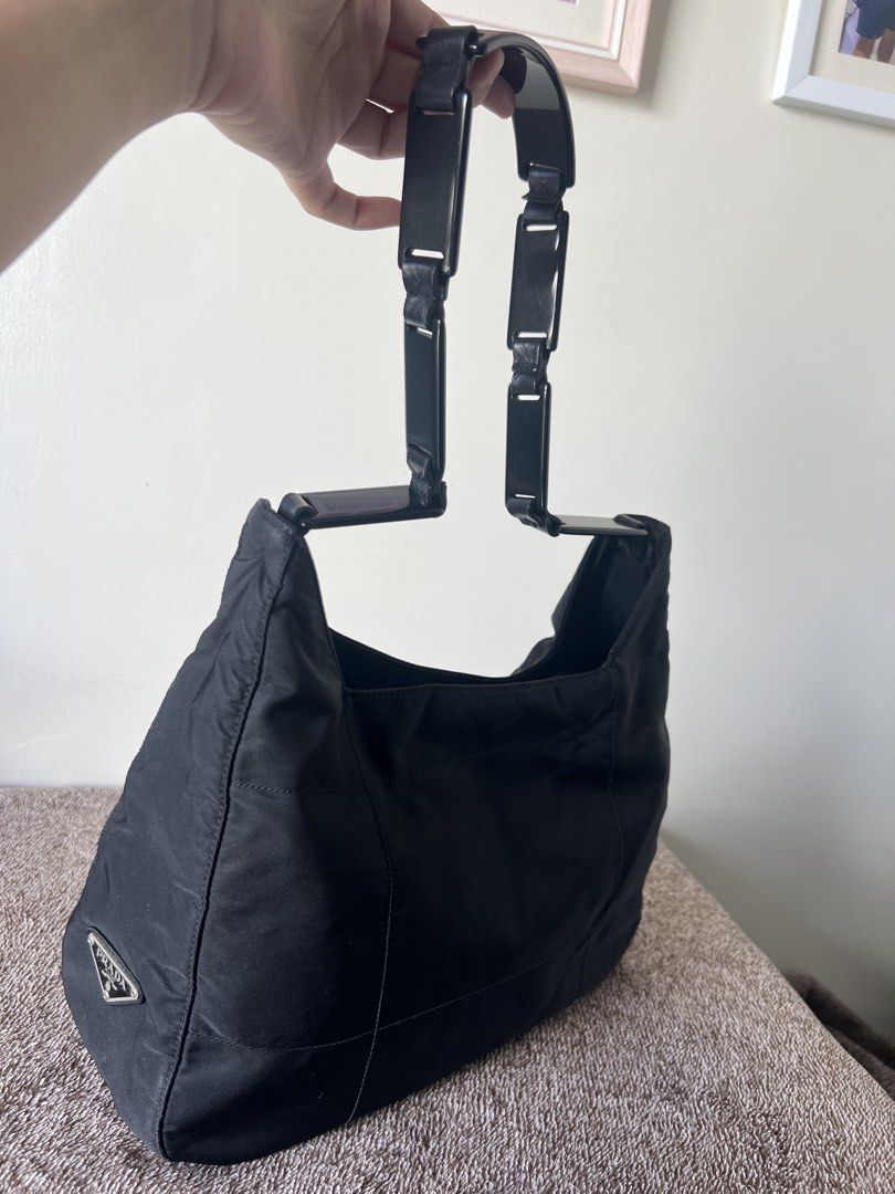 Prada Black Nylon Hobo Bag (Category: Luxury Bags & Wallets) located in Imus. Submitted by r_mercado (Listing ID 1422550684, Image 3). Description: Black Prada hobo bag. Features a nylon exterior with a triangular Prada logo on the front. The bag has a zip closure and a black interior lining. The bag has a unique handle design. Includes an interior zip pocket with a Prada label..