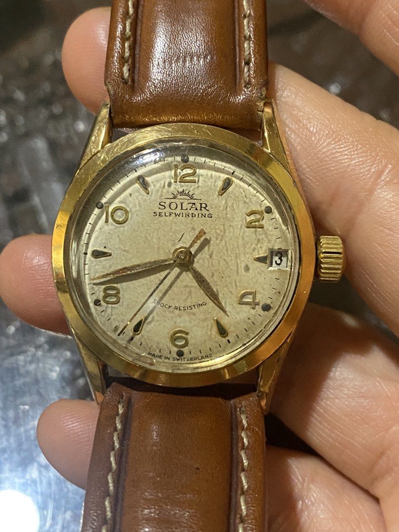 Solar Selfwinding Vintage Watch (Category: Luxury Watches) located in Manila. Submitted by roseluxuryitems (Listing ID 1422585389, Image 1). Description: Omega Speedmaster Solar Impulse Self Winding Shock Resisting Vintage Solar Selfwinding watch with a gold-toned case and a brown leather strap. The watch face is a light cream color with gold-toned numerals and hands. It features a date display at the 3 o'clock position and is marked "Shock Resis
