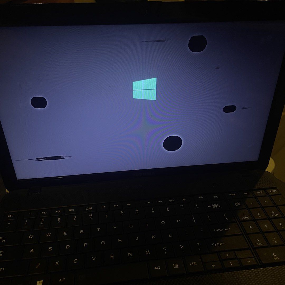 Toshiba Laptop (Category: Laptops & Notebooks) located in Paranaque City. Submitted by thriftcs (Listing ID 1422557997, Image 2). Description: - Toshiba laptop with black exterior - Displays Windows logo - Screen has some damage - Keyboard is visible.