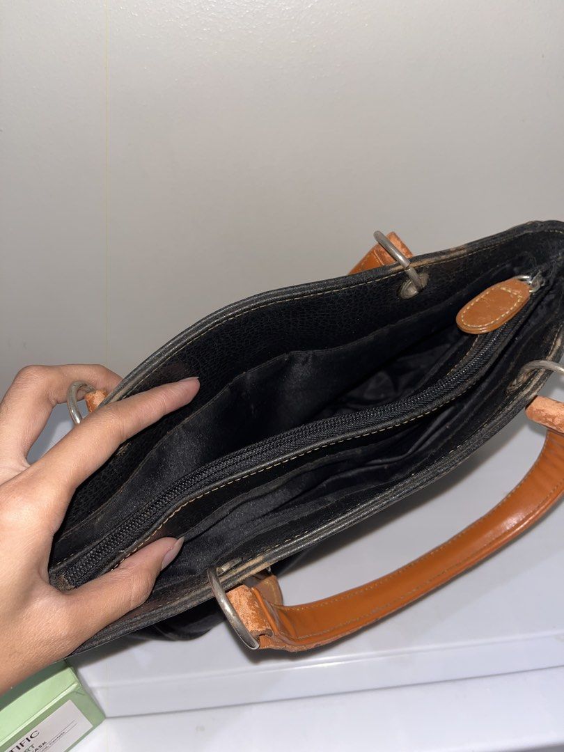 Black Handbag with Brown Handles (Category: Luxury Bags & Wallets) located in Manila. Submitted by marybelle.mb (Listing ID 1422727558, Image 3). Description: - Black handbag - Brown handles and accents - Main compartment with zipper closure - Interior zippered pocket - Exterior zippered pocket - Silver ring handle attachments - Round logo detail.
