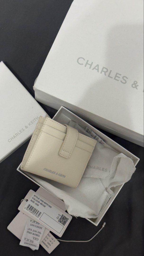 Charles & Keith Bliss Snap Button Card Holder (Category: Wallets & Card holders) located in Rizal. Submitted by marispreloved (Listing ID 1422857608, Image 1). Description: - Charles & Keith card holder wallet - Color: Beige - Features: - Multiple card slots - Snap closure - Includes: - Original box - Dust bag - Tags - Size: XXS - Authentic Charles & Keith logo visible.