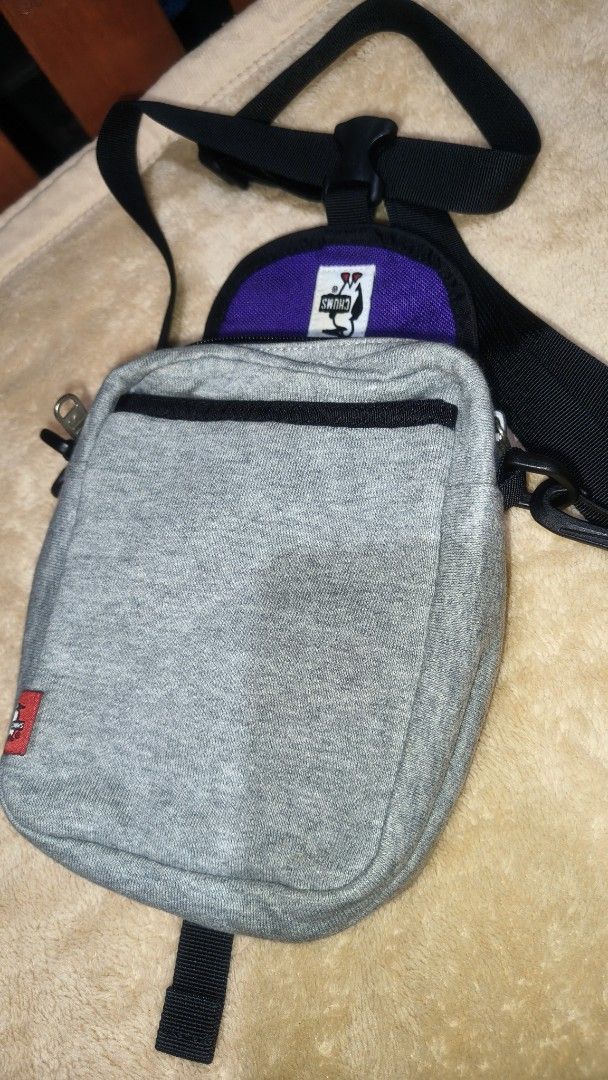 Chums Crossbody Bag (Category: Cross-body Bags) located in Tanza. Submitted by declutterolshoppe (Listing ID 1422829923, Image 3). Description: - Chums crossbody bag - Color: Gray body with purple accents - Main compartment with zipper - Front pocket with zipper - Adjustable black strap - Buckle closure - Chums logo on front - Small Chums tag on side.