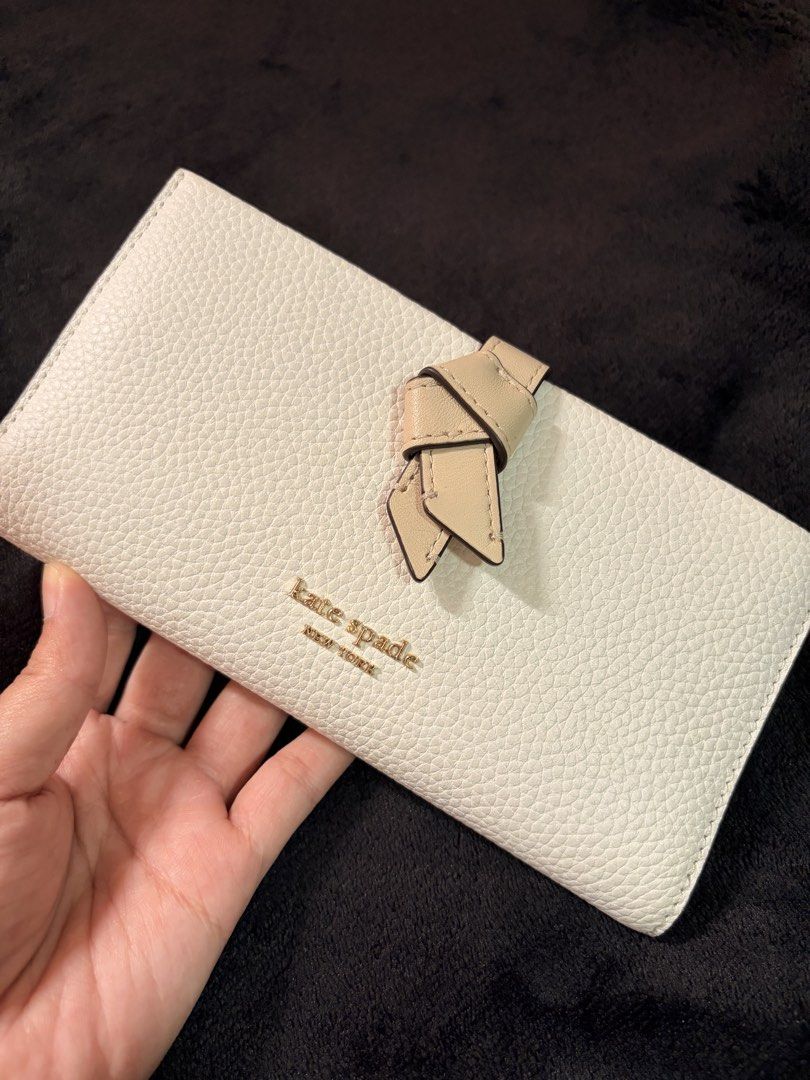Kate Spade Knot Detail Wallet (Category: Wallets & Card holders) located in Quezon City. Submitted by channelcoteng (Listing ID 1422779934, Image 1). Description: - Kate Spade long wallet - Stylish knot detail - Zip-around closure - Multiple card slots - Zippered coin compartment - Color: White with beige accent - Gold-tone hardware - Used twice - very good condition.