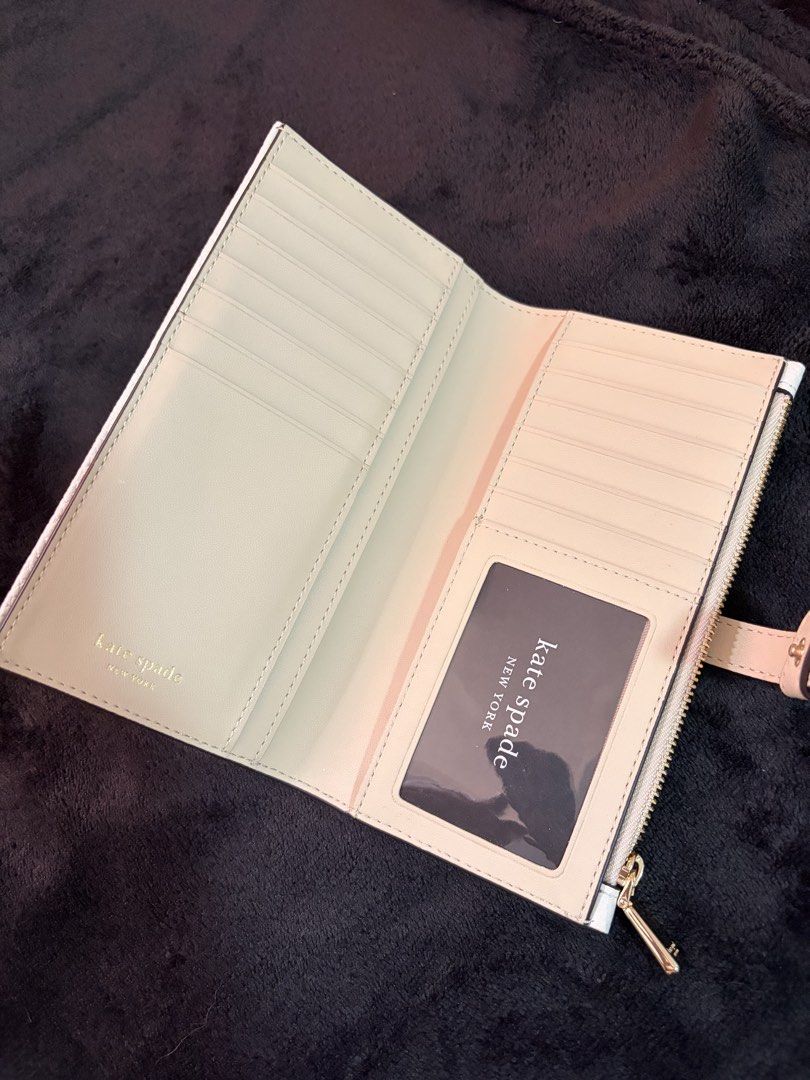 Kate Spade Knot Detail Wallet (Category: Wallets & Card holders) located in Quezon City. Submitted by channelcoteng (Listing ID 1422779934, Image 2). Description: - Kate Spade long wallet - Stylish knot detail - Zip-around closure - Multiple card slots - Zippered coin compartment - Color: White with beige accent - Gold-tone hardware - Used twice - very good condition.