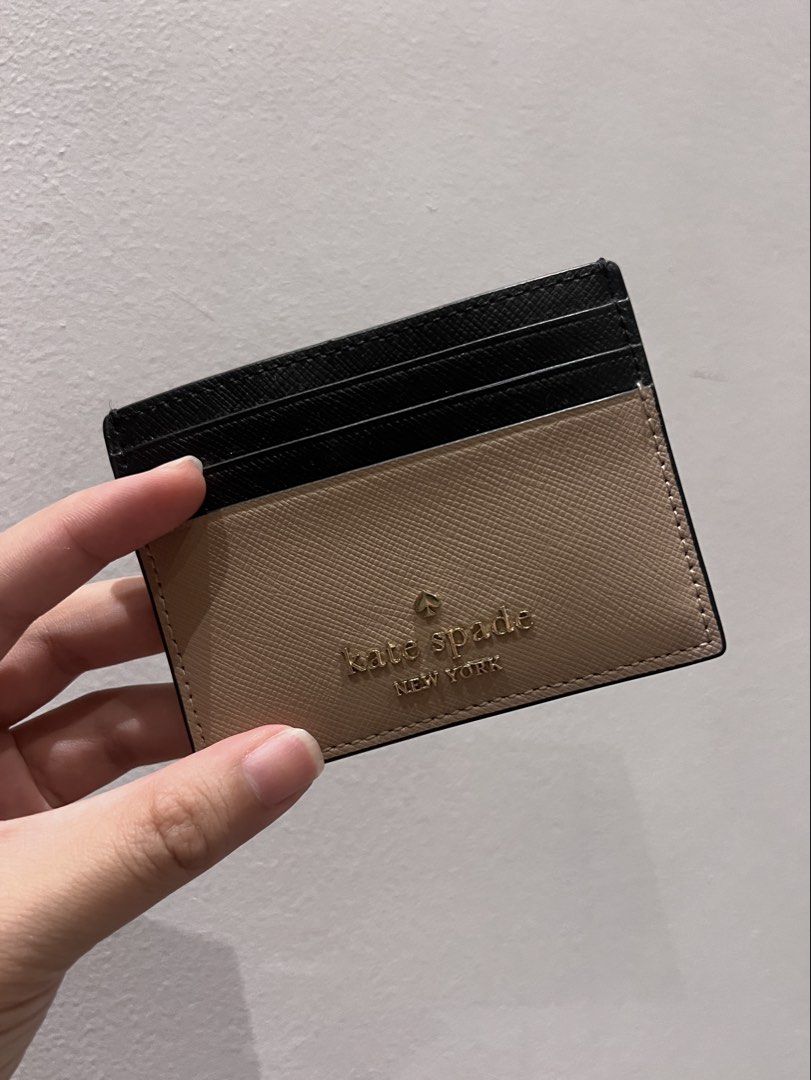 Kate Spade Madison Slim Card Holder (Category: Wallets & Card holders) located in Quezon City. Submitted by cmrls (Listing ID 1422815908, Image 3). Description: - Kate Spade Madison Small Slim Card Holdercard holder - Stylish black and tan color block design - Multiple card slots for organization - Includes Kate Spade dust bag - Features the Kate Spade logo.