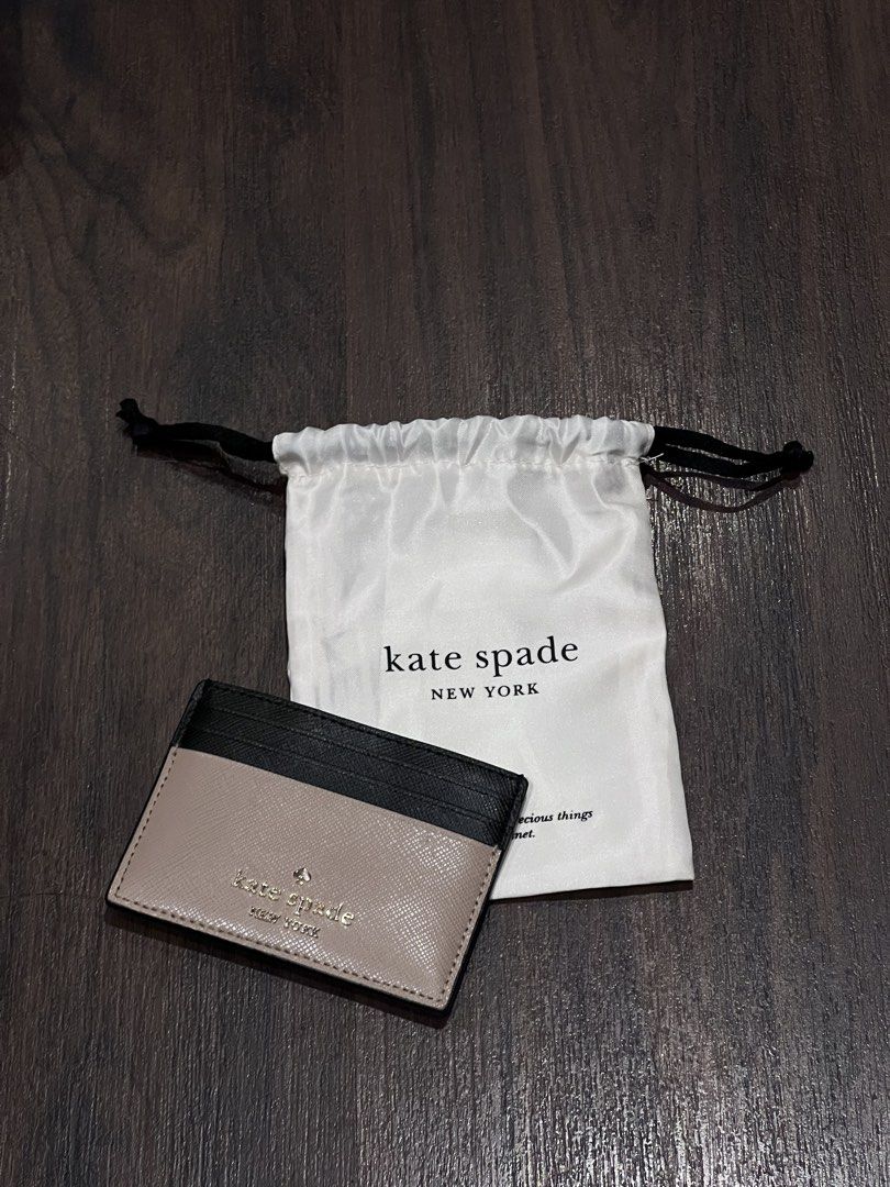 Kate Spade Madison Slim Card Holder (Category: Wallets & Card holders) located in Quezon City. Submitted by cmrls (Listing ID 1422815908, Image 1). Description: - Kate Spade Madison Small Slim Card Holdercard holder - Stylish black and tan color block design - Multiple card slots for organization - Includes Kate Spade dust bag - Features the Kate Spade logo.