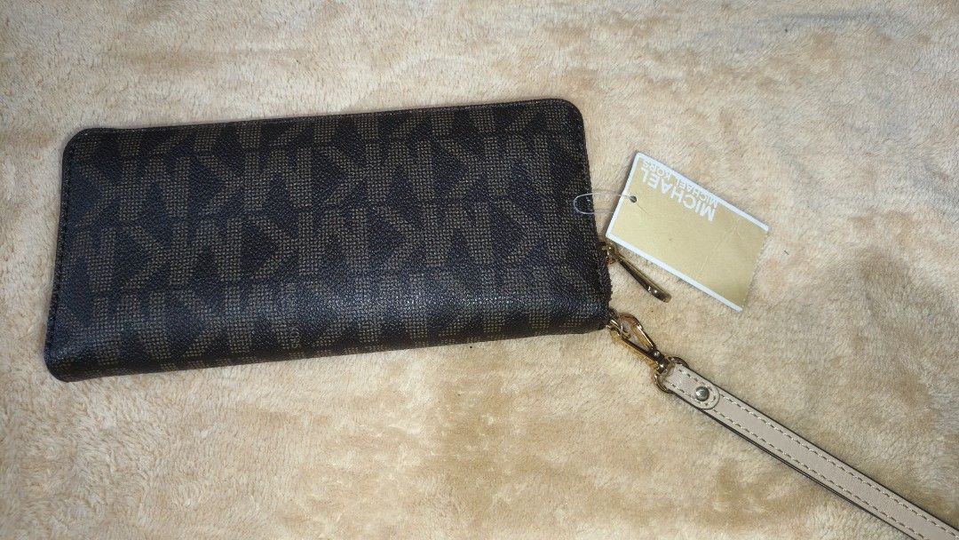 Michael Kors Zip Around Wallet (Category: Wallets & Card holders) located in Tanza. Submitted by declutterolshoppe (Listing ID 1422787599, Image 2). Description: - Michael Kors zip-around wallet - Features MK logo pattern - Includes wrist strap - Multiple card slots and compartments - Comes with original tag - Color: Brown - Hardware: Gold-tone.