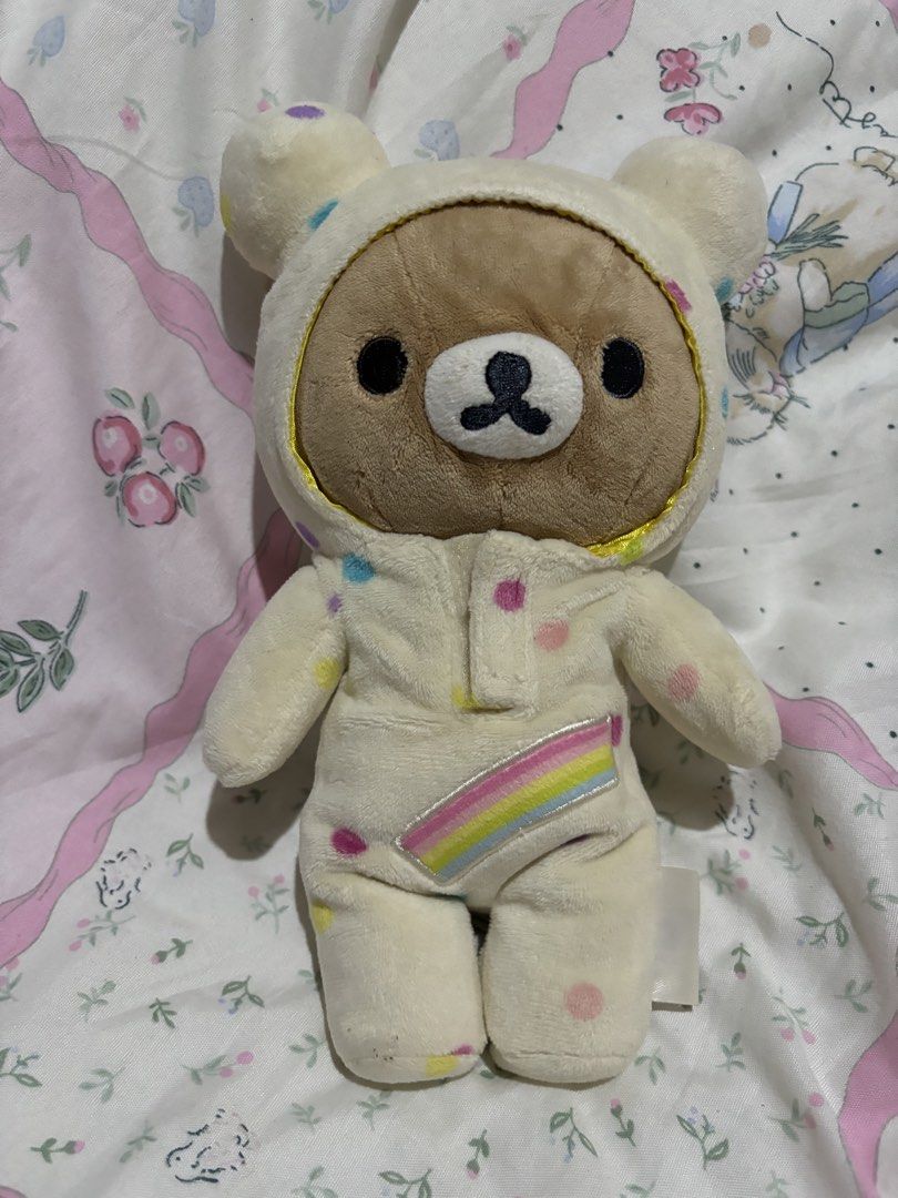 Rilakkuma Bear Plush Toy (Category: Plushies & Soft Toys) located in Manila. Submitted by meloopsy (Listing ID 1422896374, Image 3). Description: - Adorable Rilakkuma bear plush toy. - Features a polka-dot onesie with a rainbow design. - Brown-faced bear with a hood. - Soft and cuddly material. - Perfect for collectors or as a gift. - Includes a tag attached at the back..