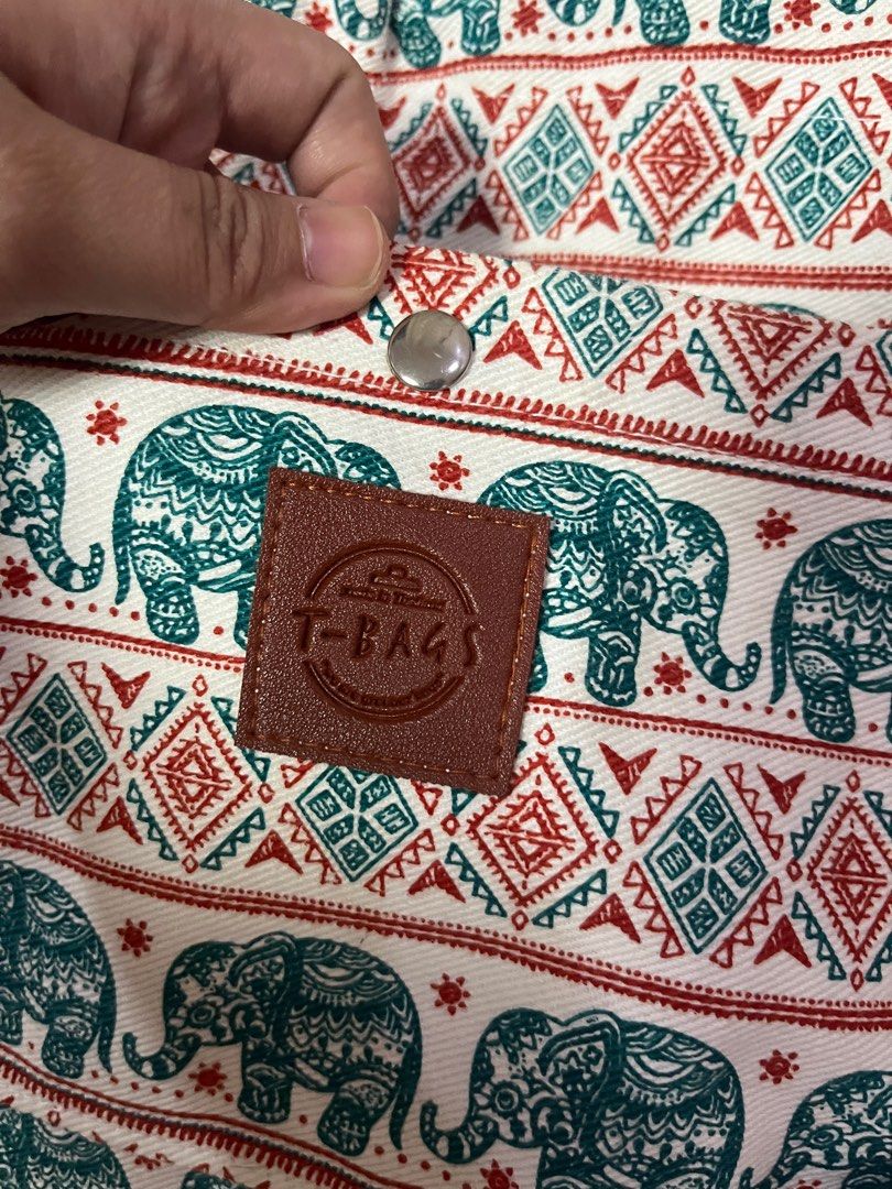 Thailand Elephant Print Drawstring Sling Body Bag (Category: Luxury Bags & Wallets) located in Antipolo. Submitted by byAdi (Listing ID 1422878601, Image 3). Description: - Elephant print drawstring bag - Rope strap and snap closure - Features a 'T-Bags' leather patch - Designed with teal and red accents on a white background - Ideal for carrying small items.