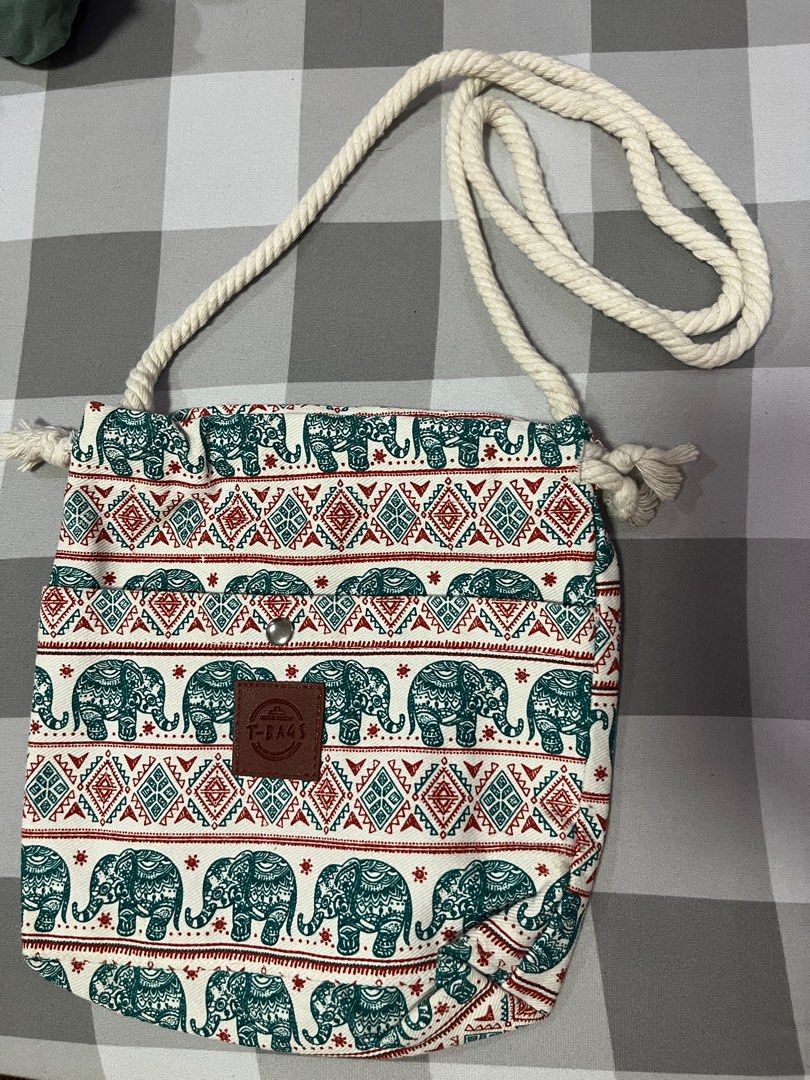Thailand Elephant Print Drawstring Sling Body Bag (Category: Luxury Bags & Wallets) located in Antipolo. Submitted by byAdi (Listing ID 1422878601, Image 2). Description: - Elephant print drawstring bag - Rope strap and snap closure - Features a 'T-Bags' leather patch - Designed with teal and red accents on a white background - Ideal for carrying small items.