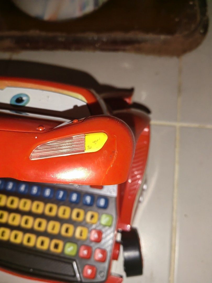 VTech Lightning McQueen Learning Laptop (Category: Laptops & Notebooks) located in Manila. Submitted by whenggsi44812 (Listing ID 1422752454, Image 3). Description: - VTech Lightning McQueen Learning Laptop - Features a screen and keyboard - Red exterior with Lightning McQueen design - Includes small car figures - Displays Cars movie characters - Shows some wear and tear.
