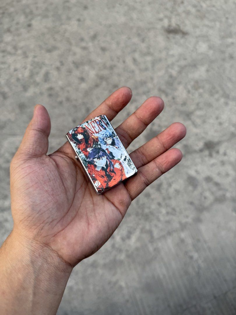 Zippo style Anime collectible lighter (Category: Accessory Holder, Box & Organizers) located in Manila. Submitted by thra_shirts (Listing ID 1422860295, Image 1). Description: This item is a collectible Zippo-style windproof lighter featuring graphic imagery from the anime series Neon Genesis Evangelion, specifically depicting the character Misato Katsuragi and the NERV organization logo. Working Need gas Excellent condition No inclusion .