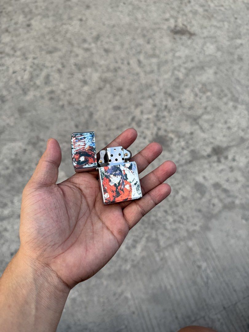 Zippo style Anime collectible lighter (Category: Accessory Holder, Box & Organizers) located in Manila. Submitted by thra_shirts (Listing ID 1422860295, Image 3). Description: This item is a collectible Zippo-style windproof lighter featuring graphic imagery from the anime series Neon Genesis Evangelion, specifically depicting the character Misato Katsuragi and the NERV organization logo. Working Need gas Excellent condition No inclusion .