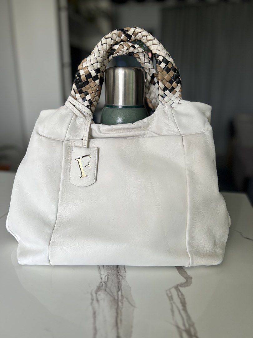Authentic Furla White Leather Tote Bag (Category: Luxury Bags & Wallets) located in Cavite. Submitted by slumbermanila (Listing ID 1423032506, Image 3). Description: - Furla white leather tote bag - Braided handles with mixed colors - Features Furla logo tag - Patterned interior lining with small pocket - Made in Italy - Minor wear on handles This is a pre-loved item sourced from thrift finds. Kindly manage expectations, as the item shows signs o