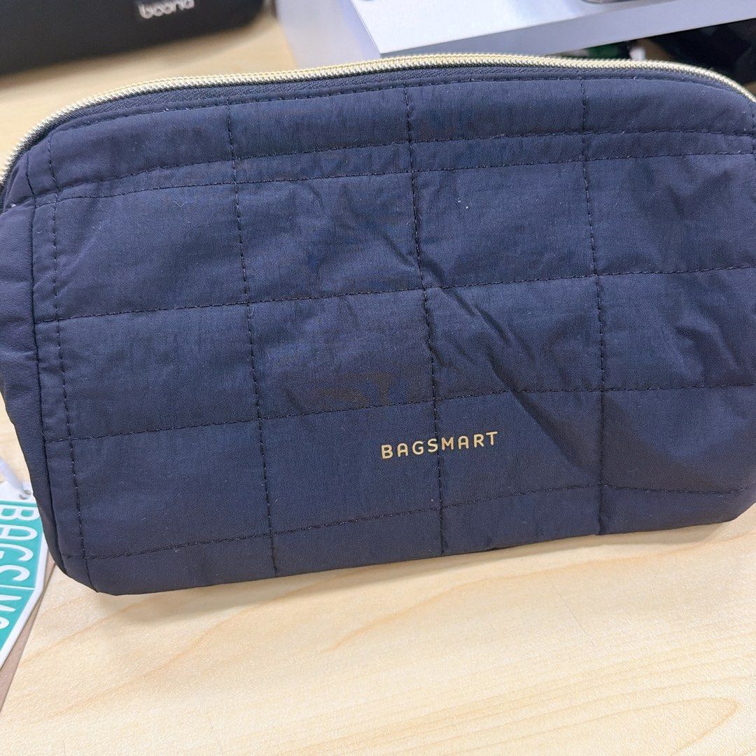 BAGSMART Quilted Cosmetic Bag (Category: Luxury Bags & Wallets) located in Quezon City. Submitted by anjlco2017 (Listing ID 1422987213, Image 1). Description: - BAGSMART cosmetic bag - Navy blue color - Gold BAGSMART logo - Quilted design - Rectangular shape - Zipper closure - Smooth, possibly nylon-like material - Neat stitching - Simple and functional design.