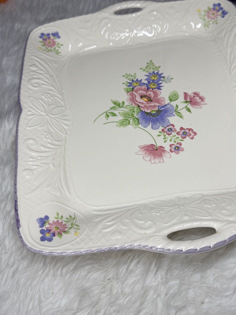 Floral Design Serving Tray with Handles (Category: Other Kitchenware & Tableware) located in Manila. Submitted by prelovedbyramiah (Listing ID 1423036161, Image 2). Description: - Floral design serving tray - Square shape with handles - White base with purple trim - Embossed floral patterns - Approximately 12 inches long.