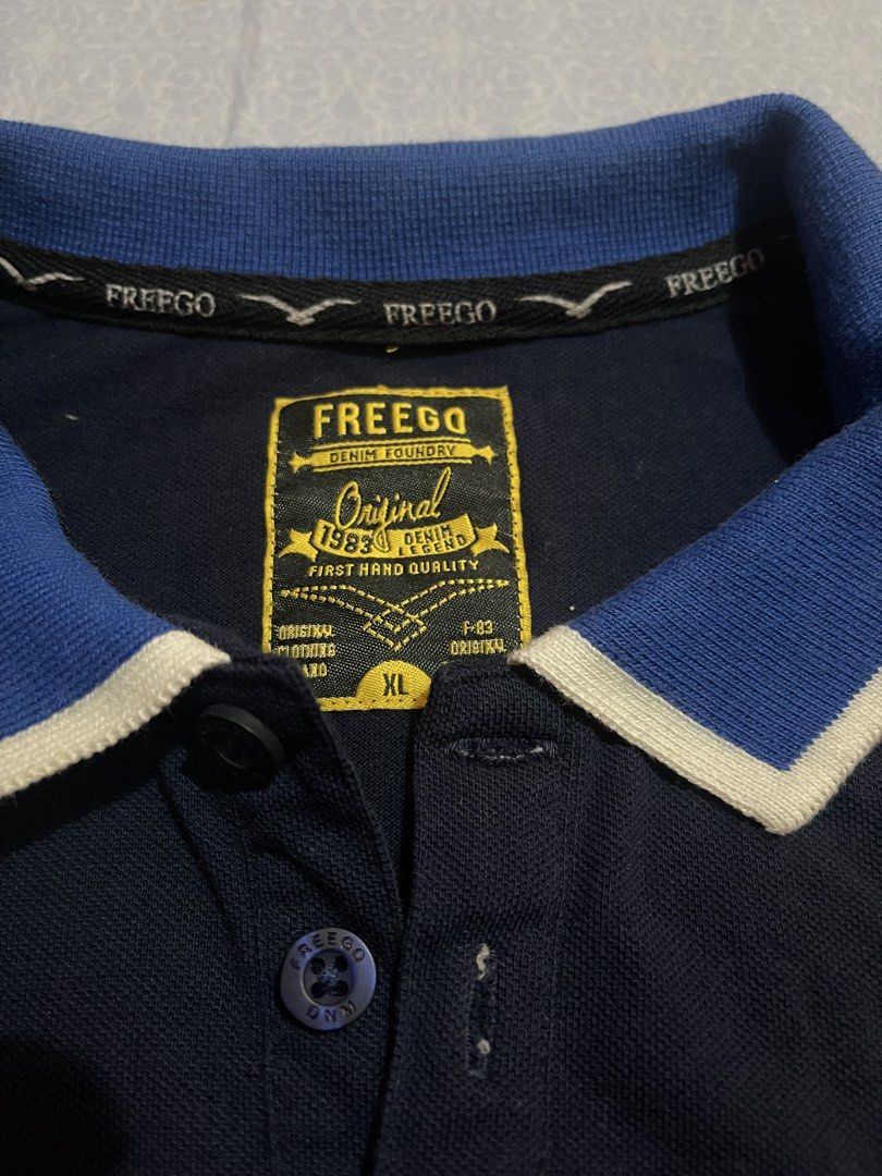 Freego Polo Shirt - XL (Category: Tshirts & Polo Shirts ) located in Manila. Submitted by mc.thrifty (Listing ID 1422963933, Image 2). Description: - Freego polo shirt - Color: Navy blue - Collar: Contrasting blue and white - Size: XL - Features: Orange sleeve trim, bird logo on chest - Details: Button closure, brand name visible.