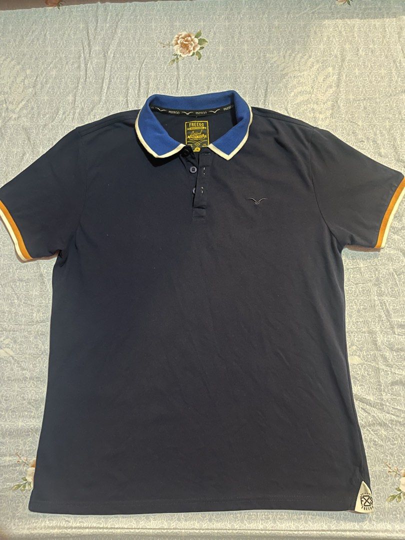 Freego Polo Shirt - XL (Category: Tshirts & Polo Shirts ) located in Manila. Submitted by mc.thrifty (Listing ID 1422963933, Image 1). Description: - Freego polo shirt - Color: Navy blue - Collar: Contrasting blue and white - Size: XL - Features: Orange sleeve trim, bird logo on chest - Details: Button closure, brand name visible.